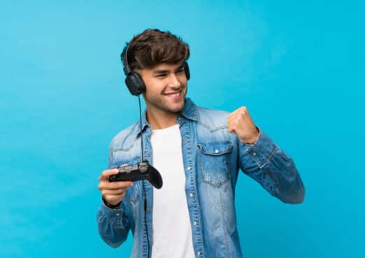 Young Handsome Man Over Isolated Blue Background Playing At Videogames